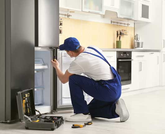 Technician performing freezer repair Orange County in a residential kitchen